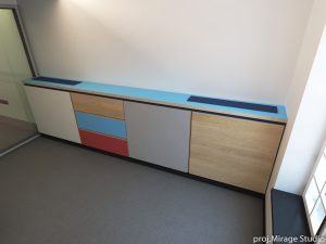 Kolorowa komoda z drewnianymi i lakierowanymi frontami w nowoczesnym biurze.